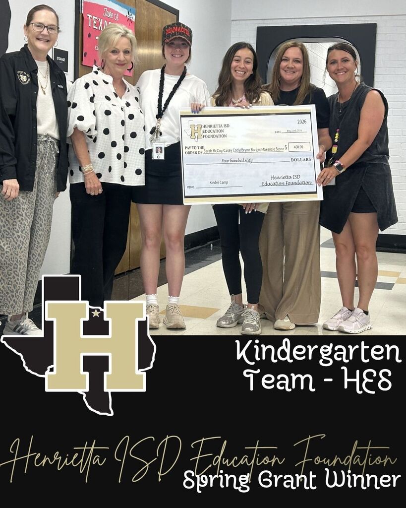 A group of women stand in a hallway, holding a check, with a school logo and text about a grant.