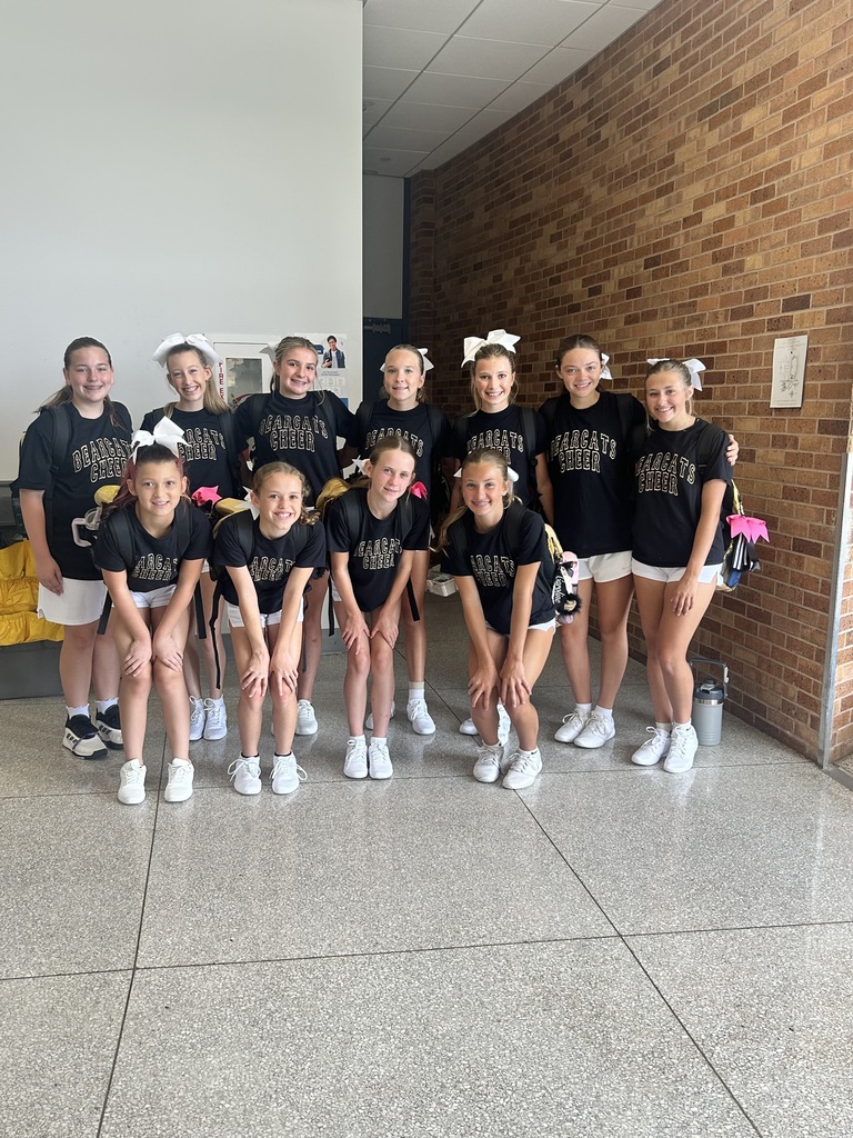 A group of young athletes in matching uniforms pose for a photo in a hallway.
