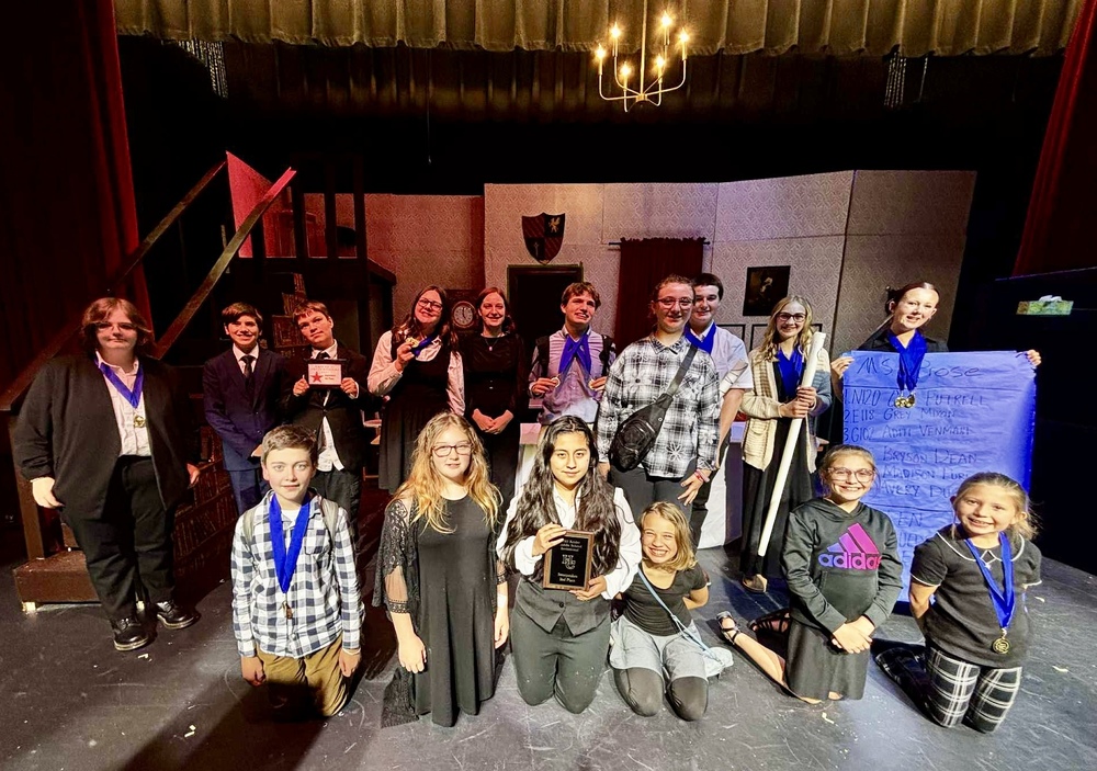 group of middle school students on a stage holding an award