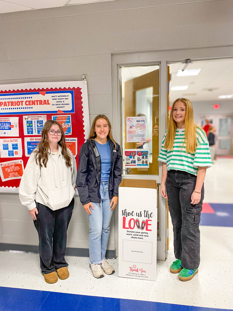 three high school girls next to box  to collect shoes