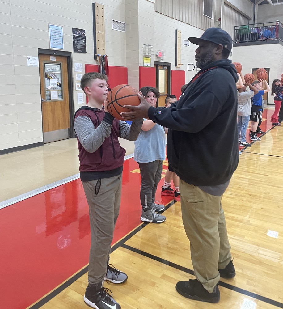 basketball coach helping student with holding ball