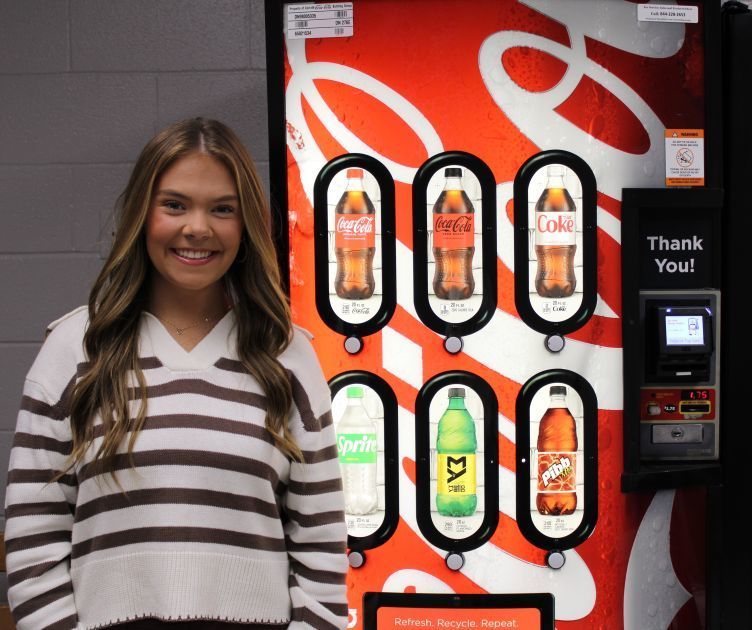 girl standing beside coke machine