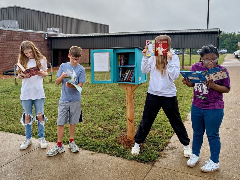 Four students reading books form little free library box