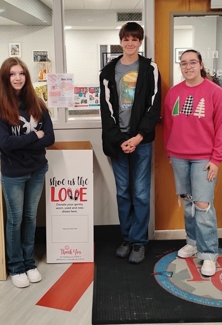 three high school students next to box  to collect shoes