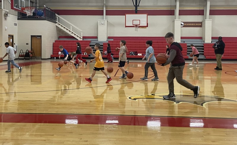 elementary school students dribble basketballs down the court