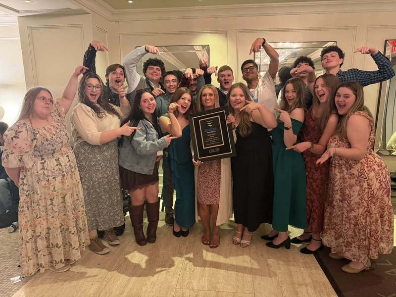 group of teens making funny faces as they hold award