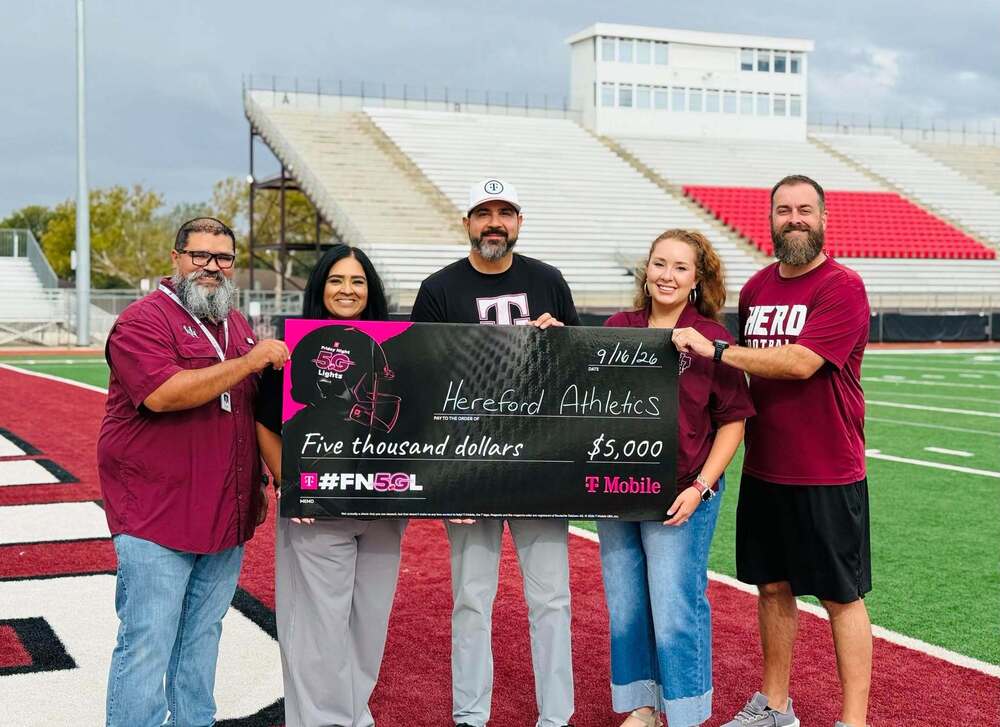 Herd team with TMobile representative receiving a check on the football field