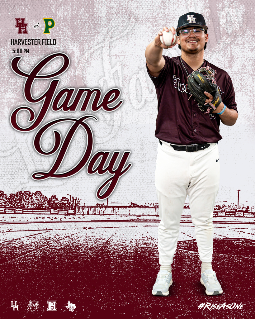 A baseball player stands on a field with a baseball glove and ball. He wears a maroon shirt, white pants, and a hat.