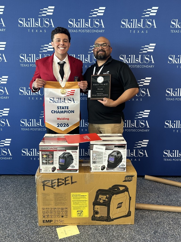 Two men stand next to a box of welding equipment, one holding a certificate and a trophy.