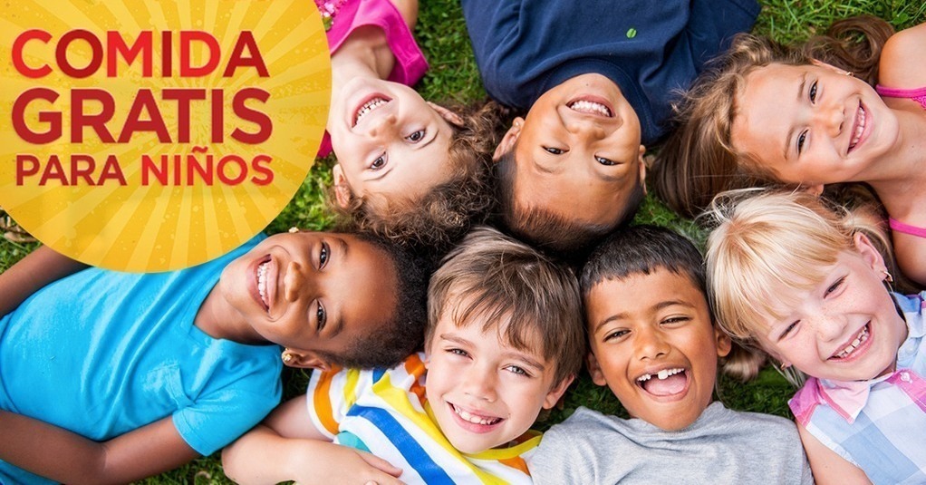 Kids lying on grass with smiles, a yellow banner with bold text overlay reading "Comida Gratis Para Niños".
