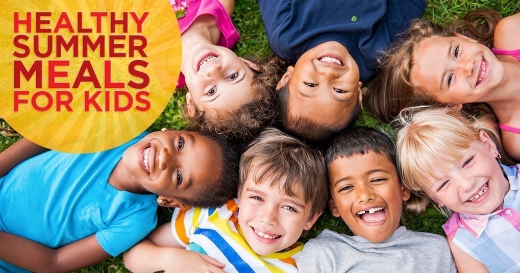 Nine children lie on grass, smiling. A yellow circle with text "Healthy Summer Meals for Kids" is above them.