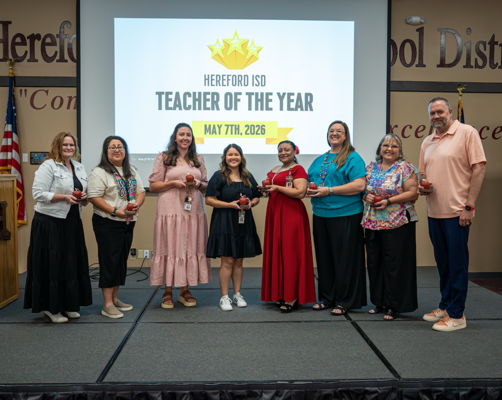 Group of seven educators on stage holding awards. Screen behind them reads Hereford ISD Teacher of the Year May 7th, 2020.