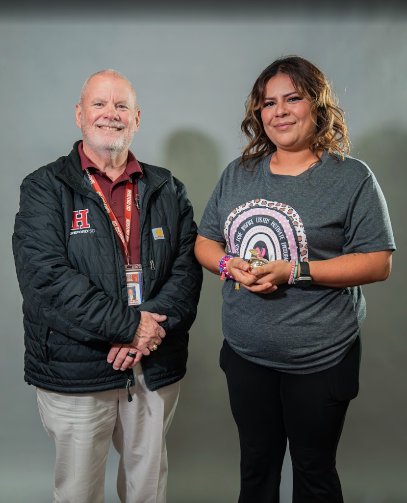 Man and woman standing close to each other. Both smiling and looking at the camera.