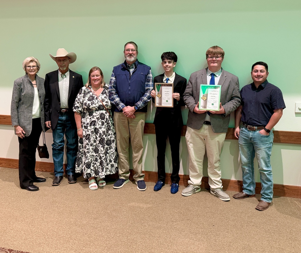 Group of award receipients against a green wall 
