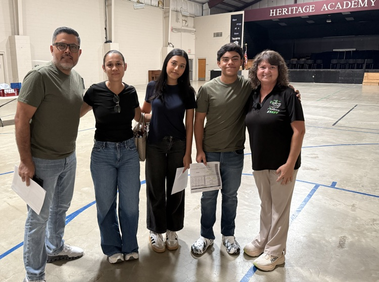 family of four with a female staff member posing inside a gym 