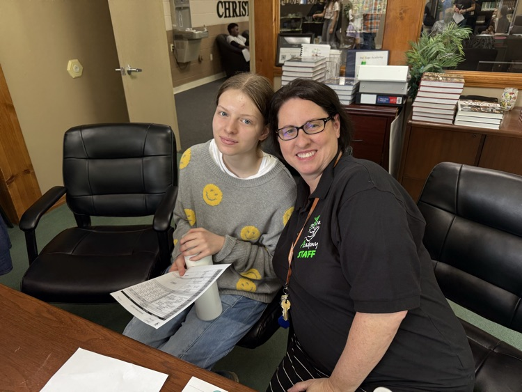 mother and teenage daughter sitting at a desk smiling 