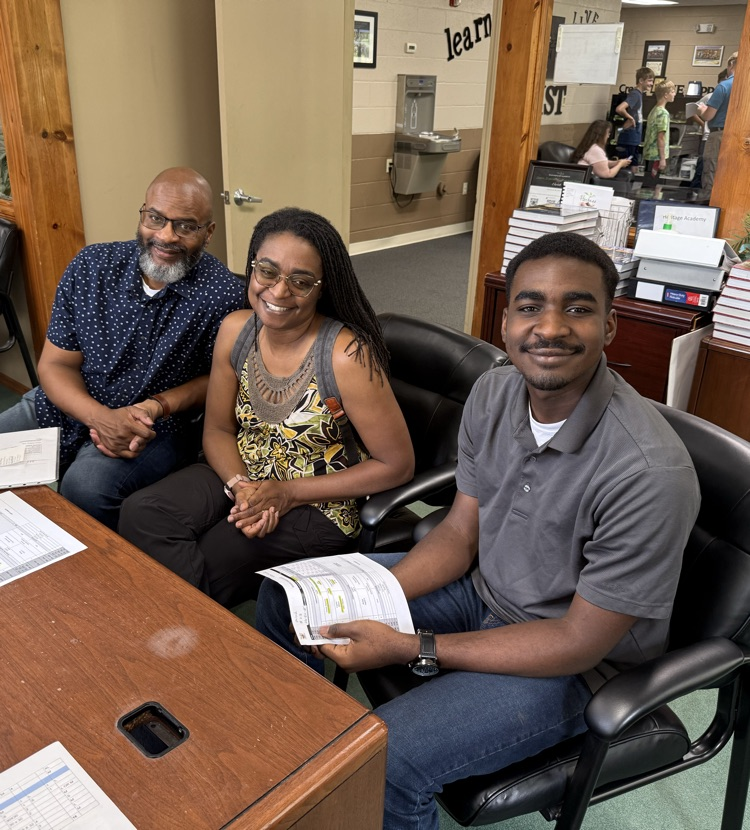 family with teenage son sitting at a desk waiting to get registered 