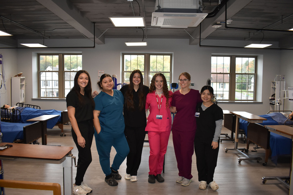 Six adult LPN students posing together in practice lab