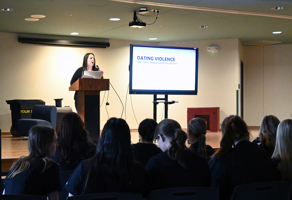 Catholic Charities presenter on stage as students look on