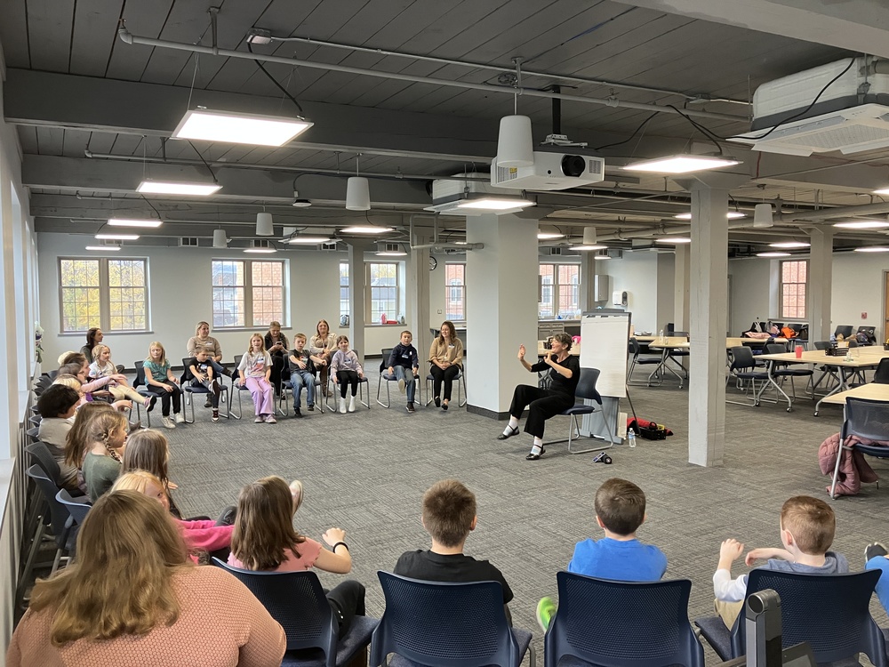 Students sitting in chairs listening to storyteller Regi Carpenter