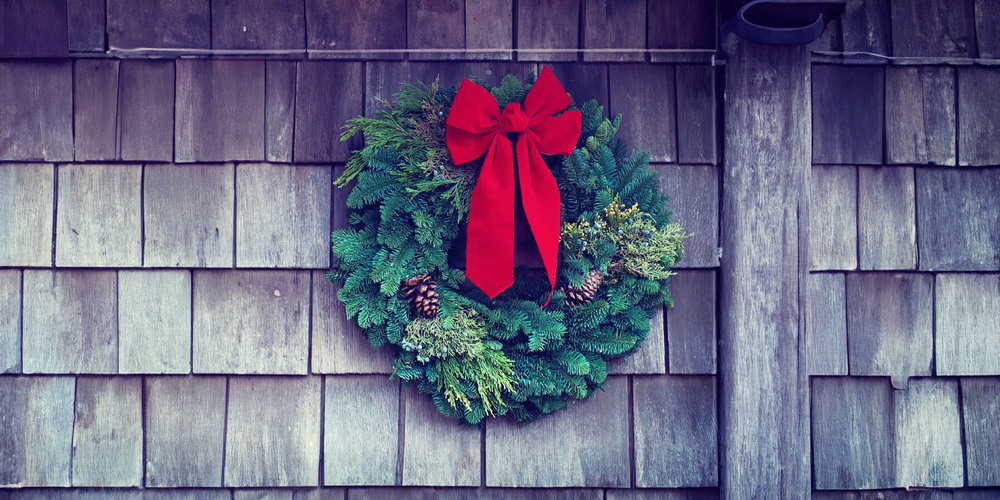 Natural wreath with a red bow hanging on siding