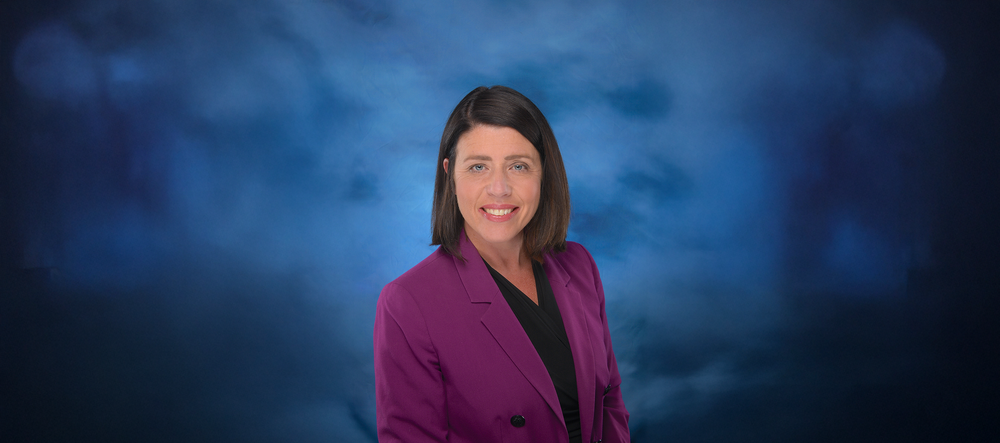 Jessica Poyer in front of a blue backdrop