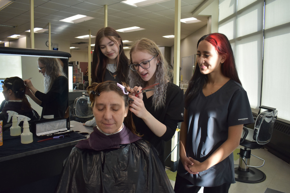 Student cutting mother's hair as two other students look on