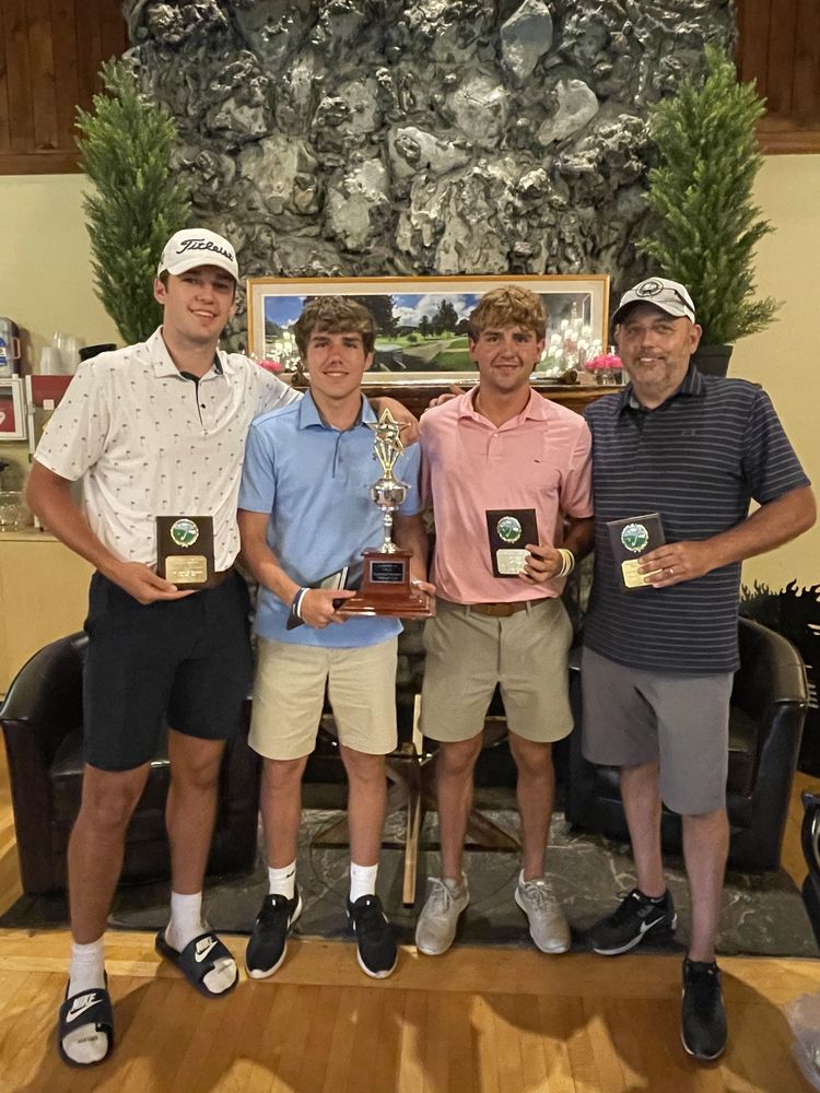 Four members of a golf team holding plaques and trophies including District Superintendent D.J. Shepardson