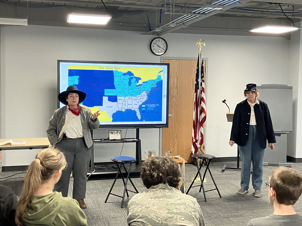 Two performers wearing clothing for Civil War presentation and presenting to eighth graders