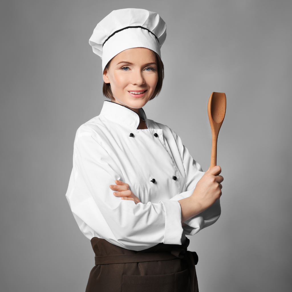 A woman in chef gear and holding a wooden spoon