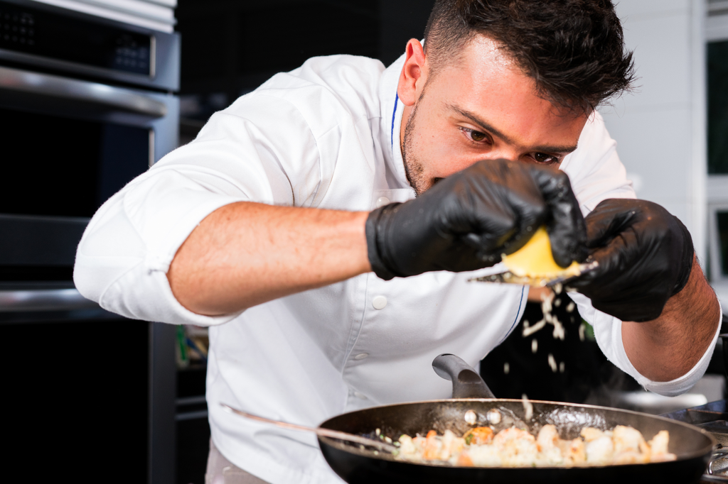 Man adding ingredients to a frying pan of food