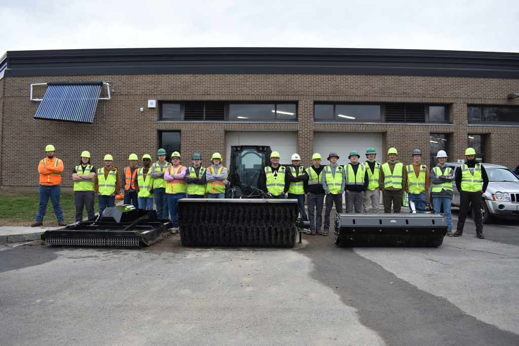 Heavy Equipment Repair Operations juniors by a skid steer and three attachments outside the BOCES building