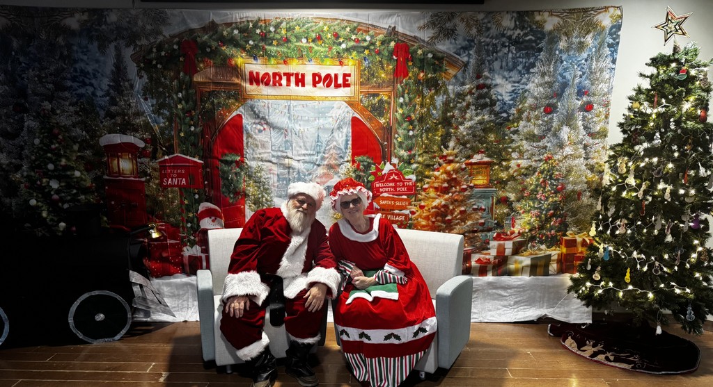 Santa Claus and Mrs. Claus in front of a holiday backdrop
