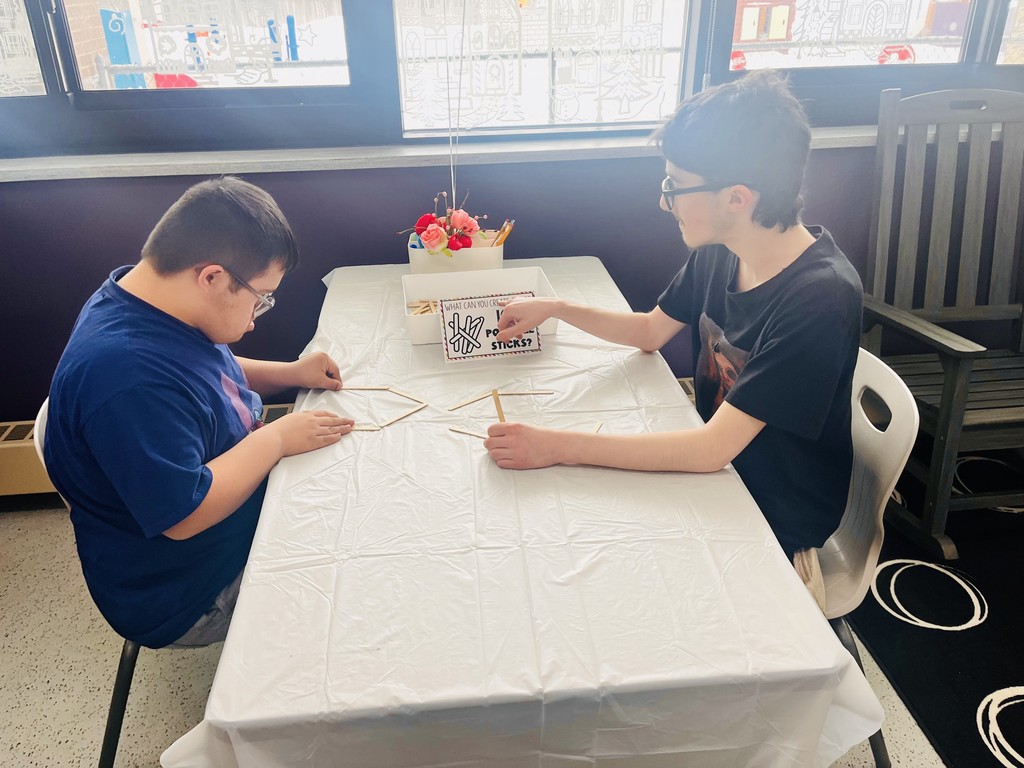 Two students working together with sticks at  a table