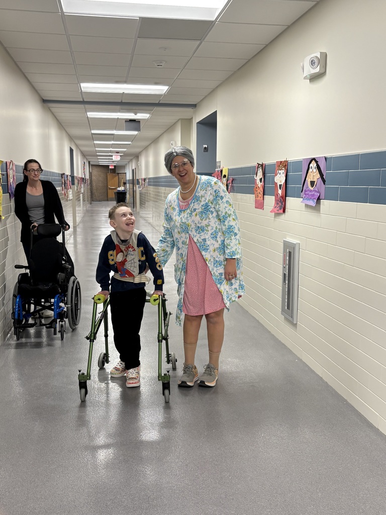 Three people walking down a hallway including a physical therapist dressed up as a 100-year-old