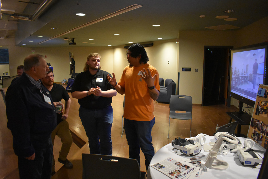 People talking near a table with VR equipment