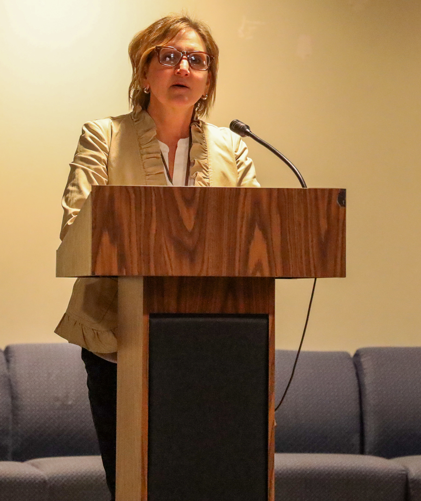 Tracy Facchini speaks at a podium on stage