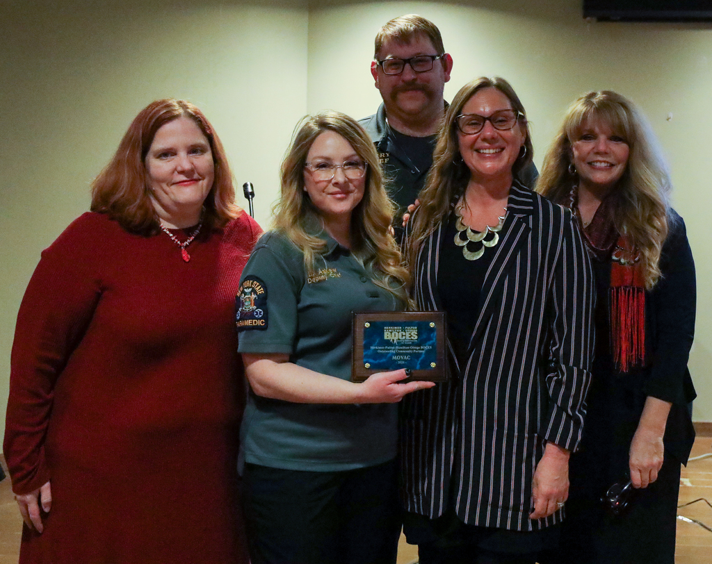 Three School to Careers representatives posing with two MOVAC representatives on stage with plaque presented to MOVAC