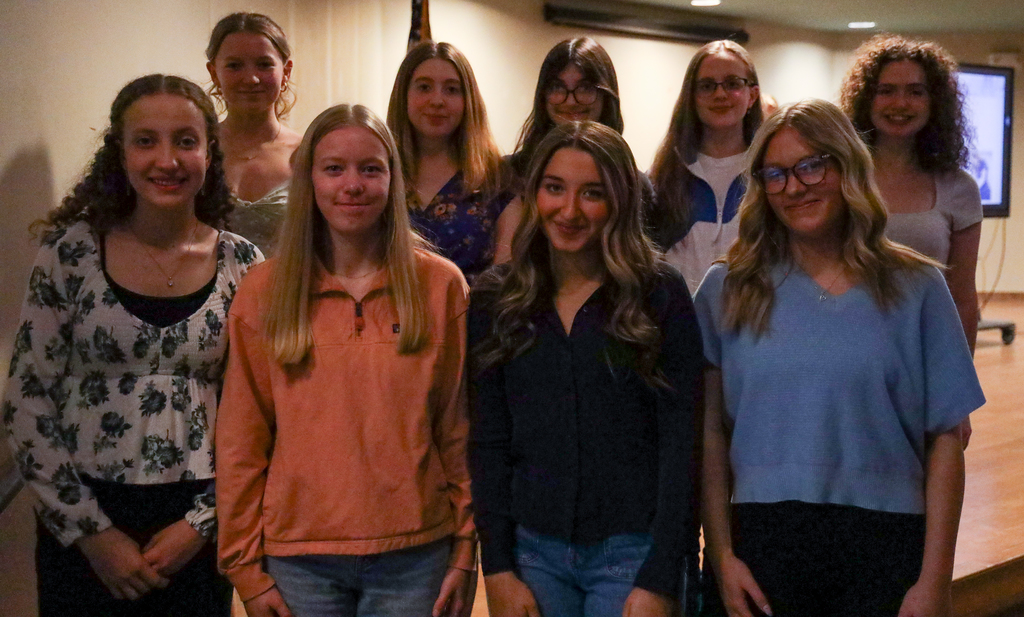 Nine student board members posing together on stage