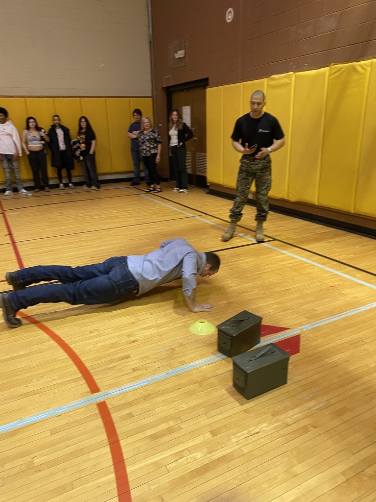 Marine Corps Staff Sgt. Paredes standing with a person doing pushups and others looking on