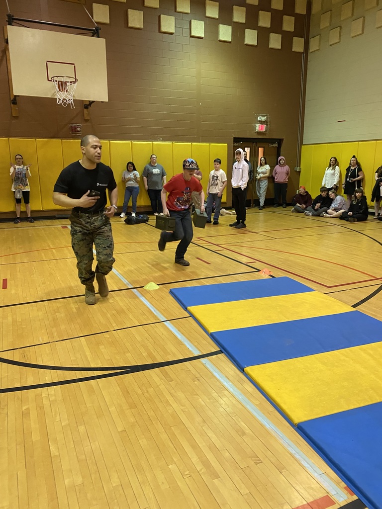 Marine Corps Staff Sgt. Paredes and a student running in the gym with other students looking on