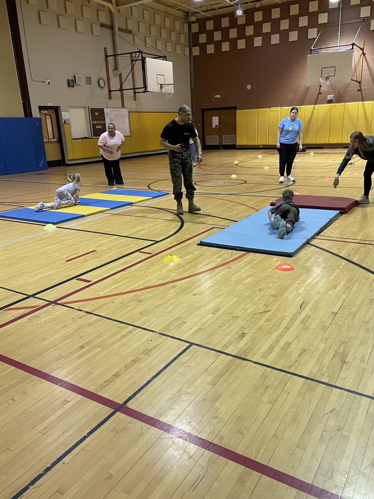 Marine Corps Staff Sgt. Paredes, students and staff in the gym with students exercising on mats