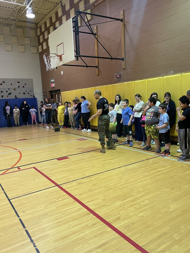 Marine Corps Staff Sgt. Paredes speaking to a large group of students in the gym