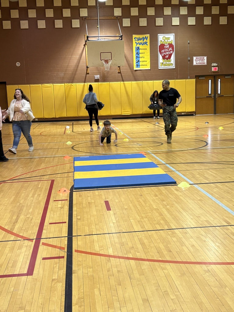 Marine Corps Staff Sgt. Paredes running and a student crawling on the gym floor with others nearby