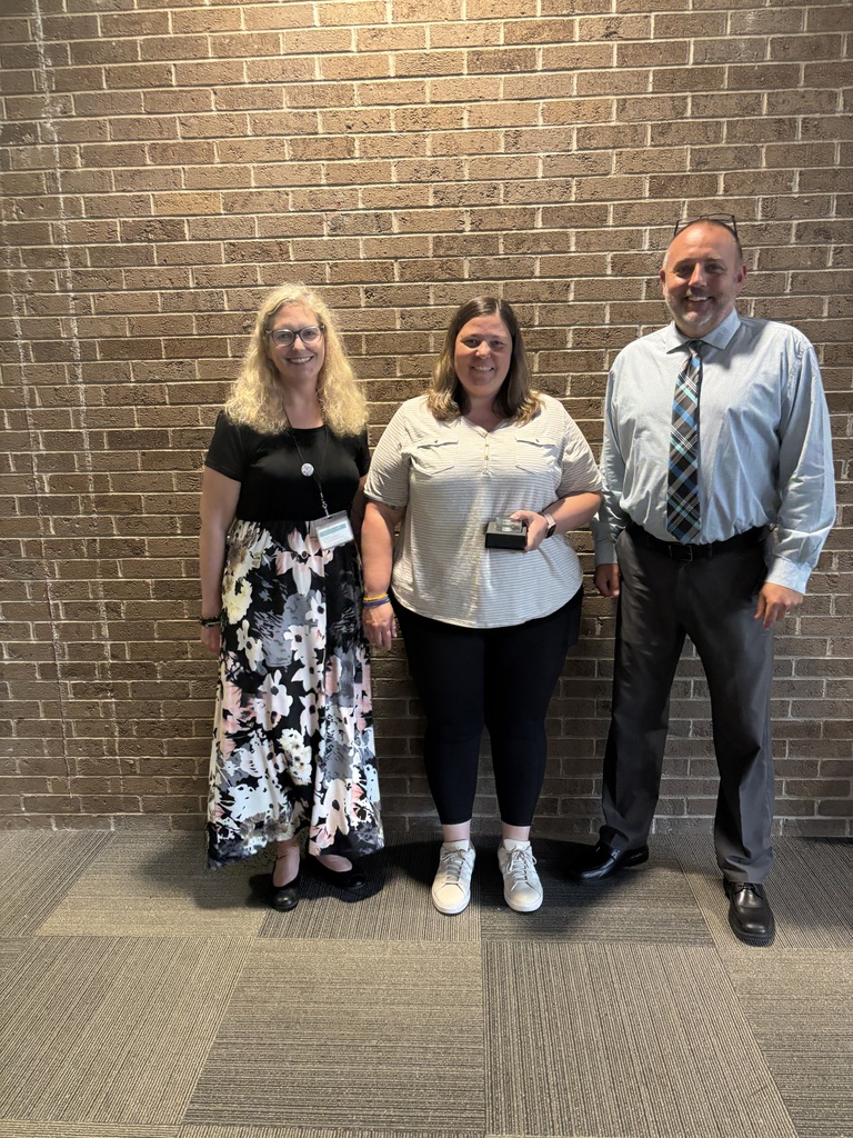Three people posing by lobby wall