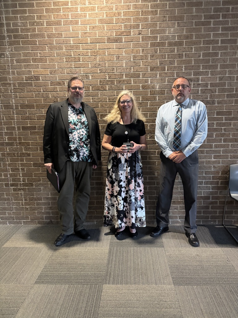 Three people posing by lobby wall