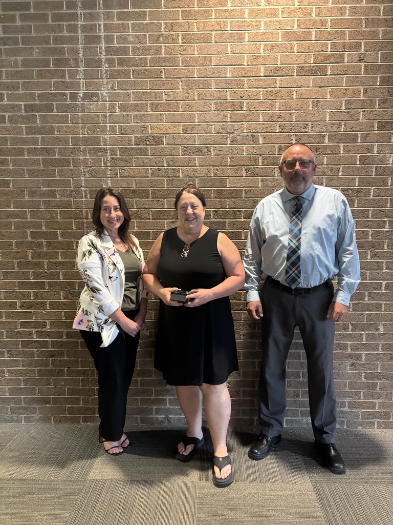 Three people posing by lobby wall