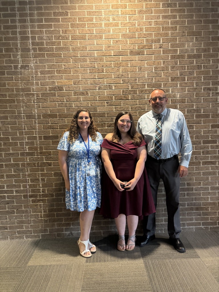 Three people posing by lobby wall
