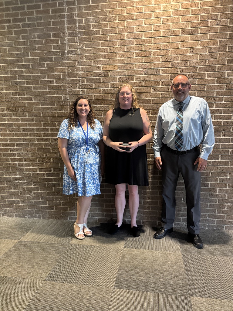Three people posing by lobby wall