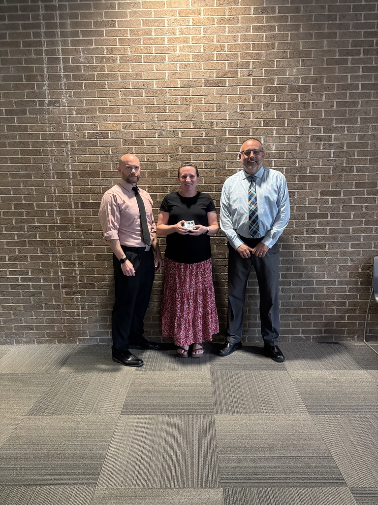 Three people posing by lobby wall